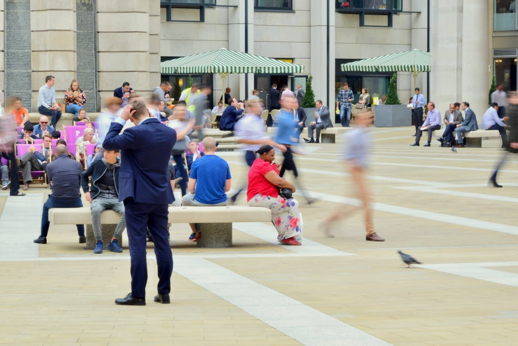 People wearing business clothes walking in different directions on a busy plaza.