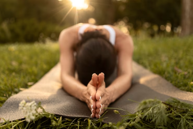 Woman doing yoga on matt in the grass.